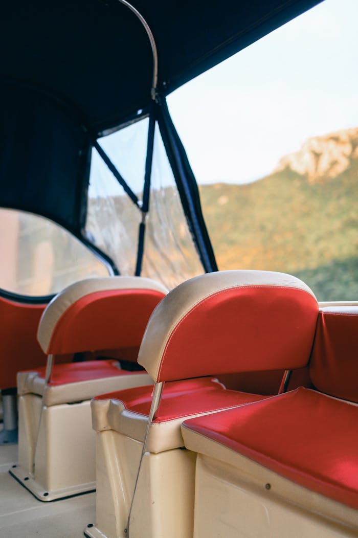 View of red seats inside a boat with mountains in the background.